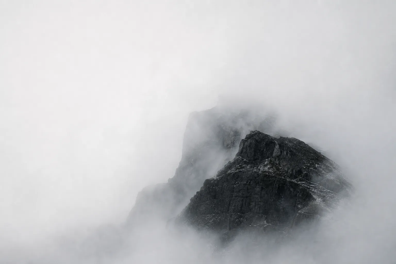 Dark stone emerging through dense white fog.
